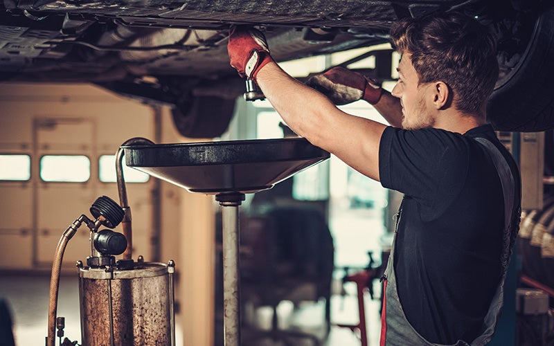 Mechanic performing an oil change on a Chevrolet vehicle in a service garage